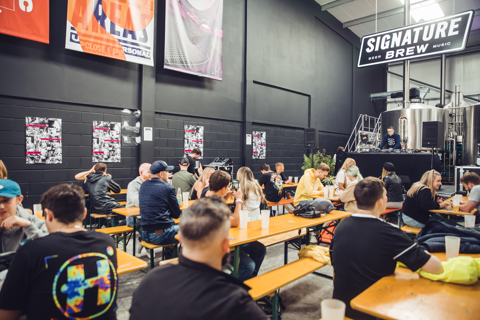 Inside Signature Brew Blackhorse Road, including long wooden benches and people drinking craft beers.