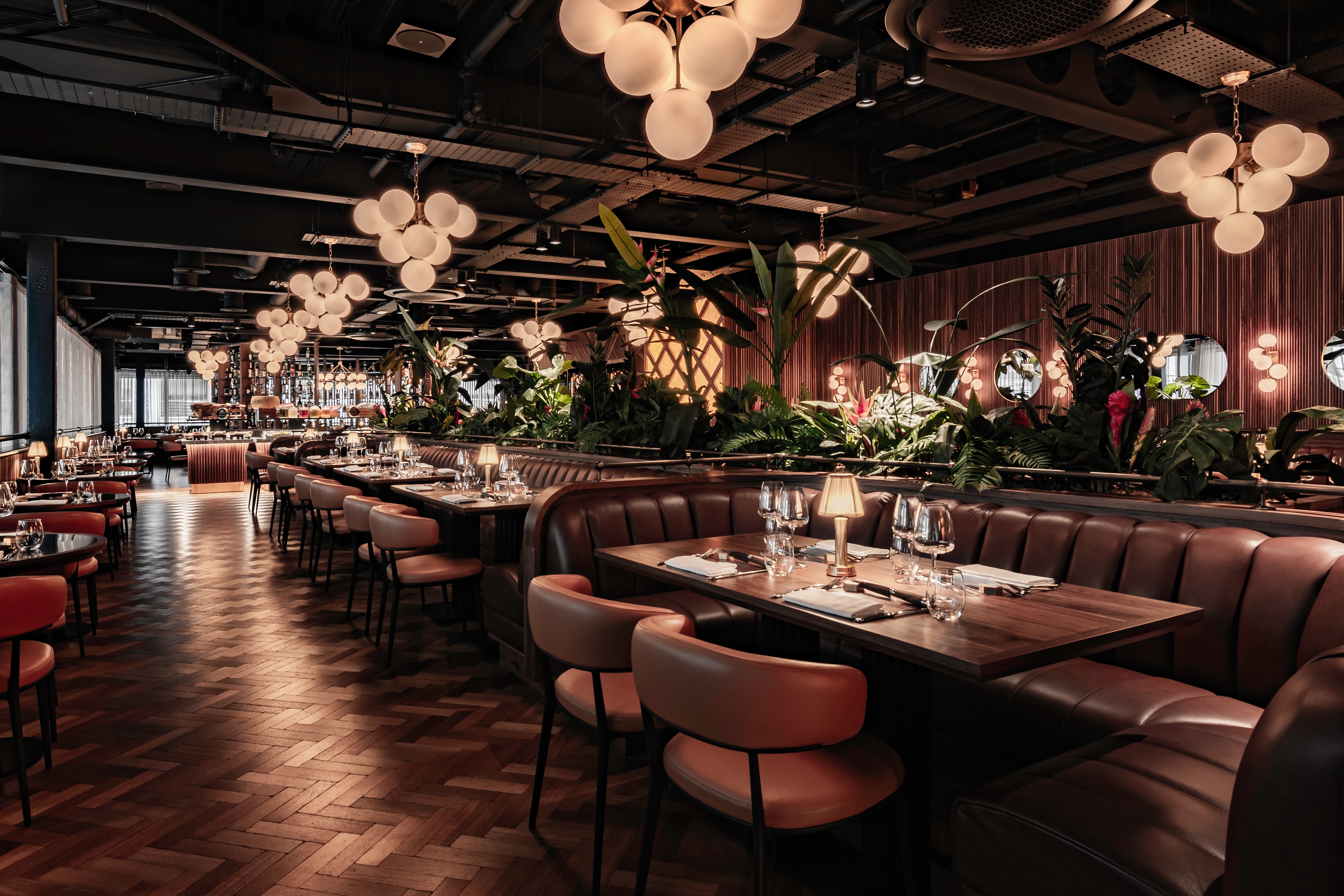 Interior image of Fazenda Bishopsgate's dining room, including leather booth seating, parquet floors and luscious indoor plants.