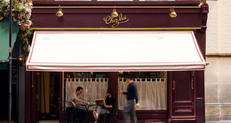 The outside of Chez Lui Notting Hill, featuring two men drinking coffee and sitting on the outside tables.