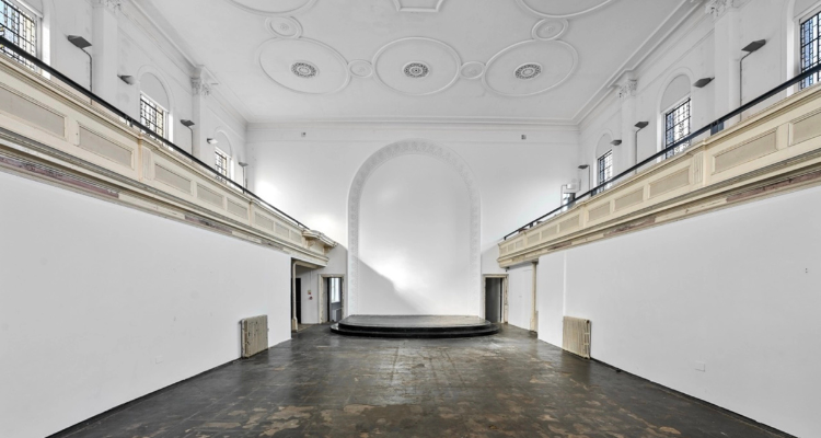 The inside of Camden Arts Centre - tall white walls, an ornate ceiling and dark wood flooring..