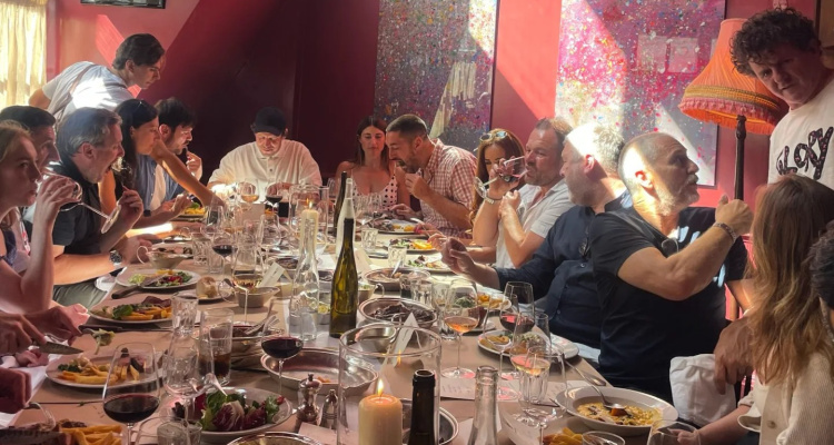 A group seated at a long table tucking into a table full of feasting menu dishes in The Devonshire's red private dining room.