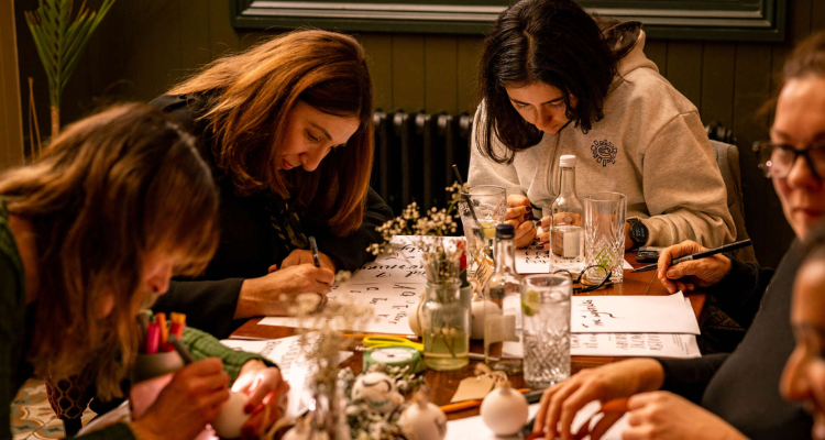 People crafting Christmas baubles around a table.