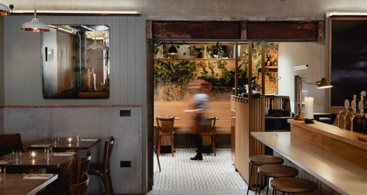 Interiors of Fire & Wine by Boxcar, including candlelit tables, green plants and wooden accents.