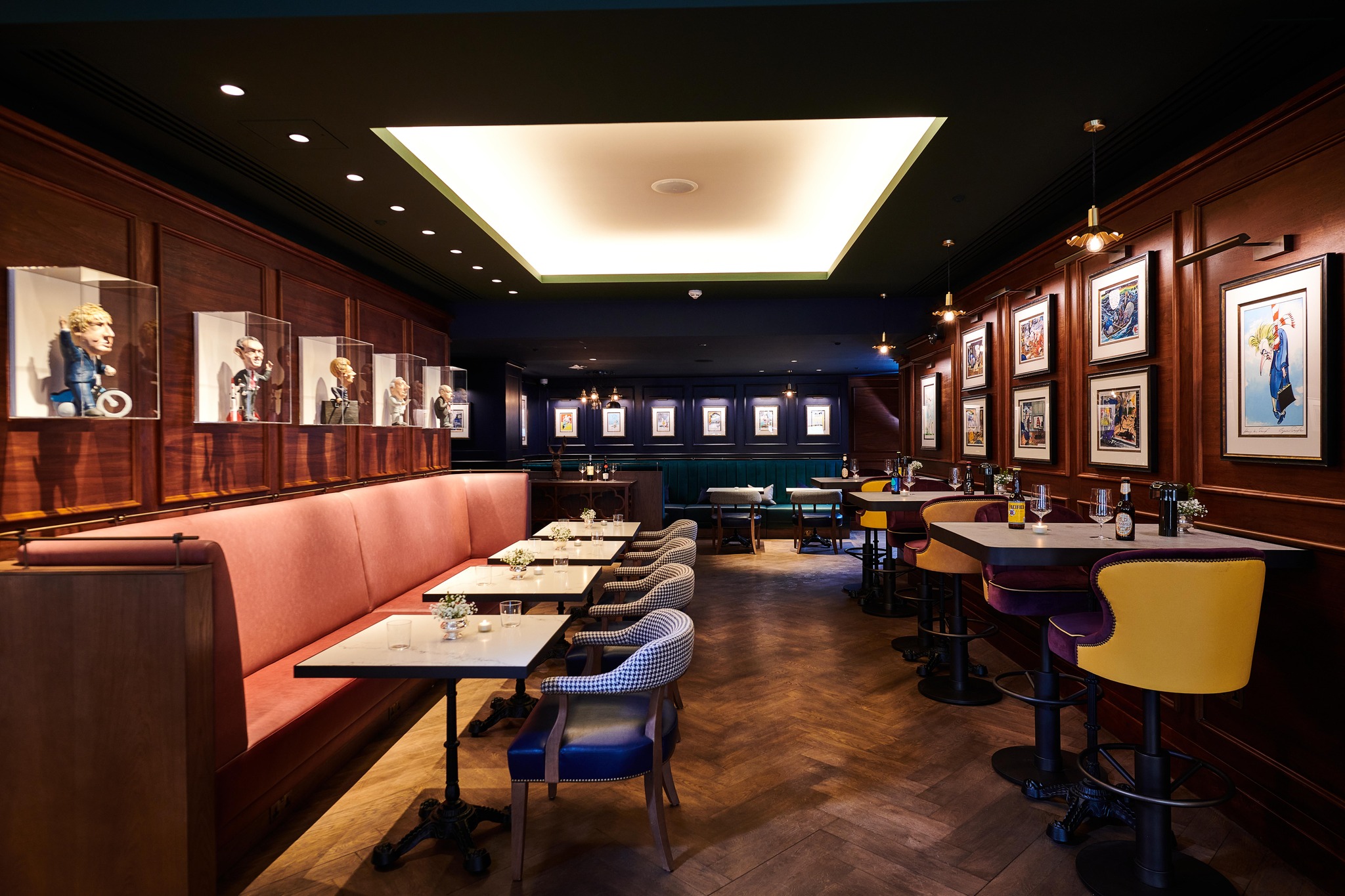 Interiors of Blue Boar Pub in Westminster, featuring parquet floors, booth seating and illustrations on the walls.