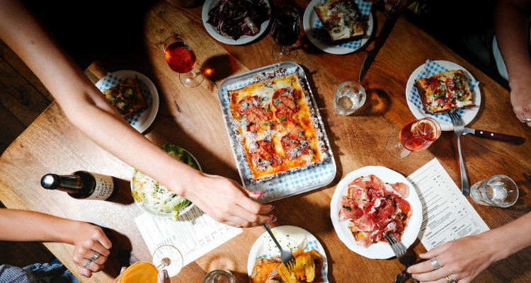 People sharing Ria's Detroit pizza from Soho.