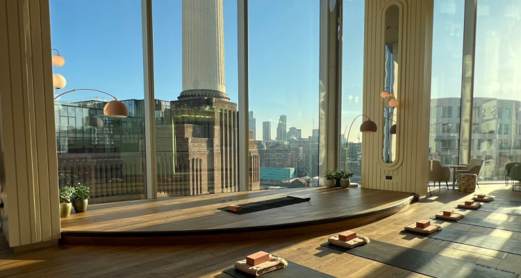 Yoga mats and blocks lined up in front of floor-to-ceiling windows with Battersea Power Station in the background.