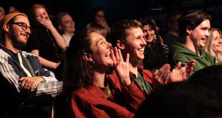 People laughing in a crowd at comedy.