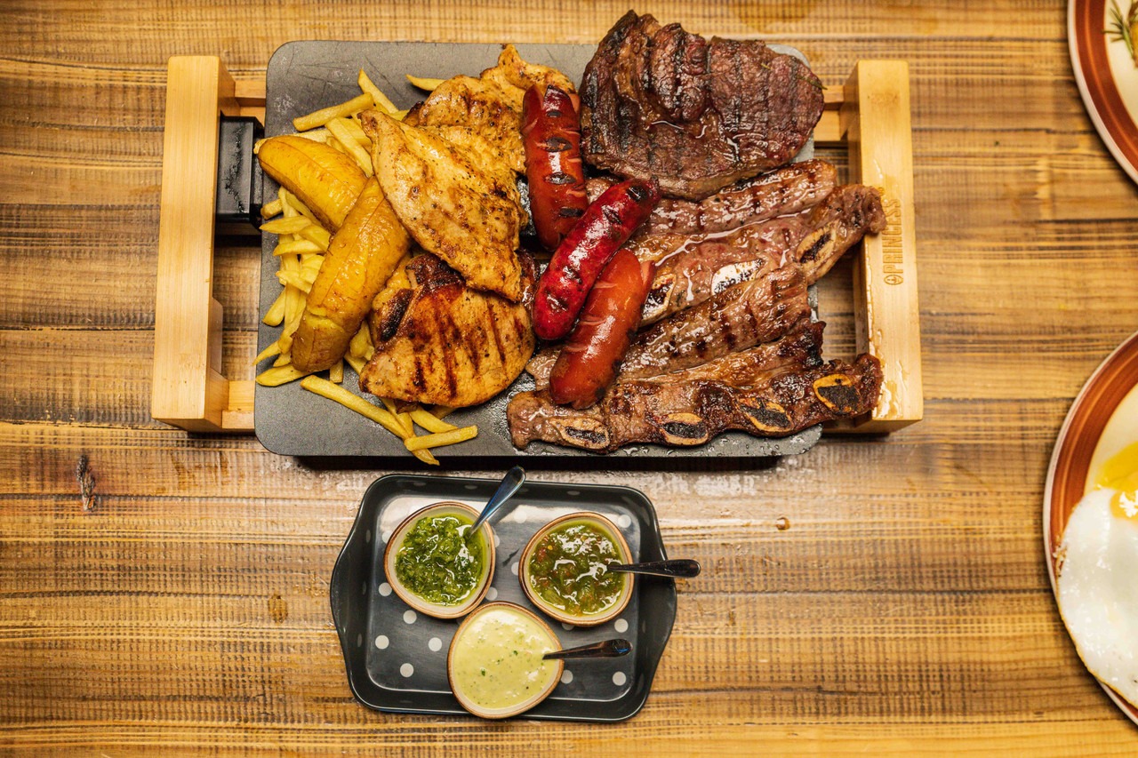 Meat platter at La Brasa in Elephant and Castle, featuring chicken, sausage, steak, chips, plantain and more.