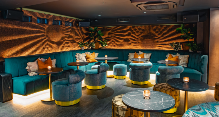 A picture of the gorgeous interiors at Viajante87 London, showcasing teal chairs, towering foliage and patterened walls. 