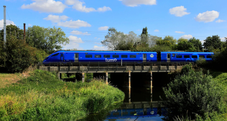 A Blue Lumo train crosses a bridge. 