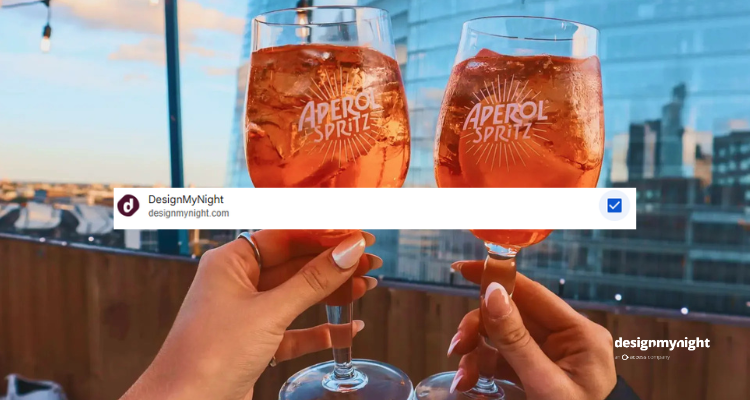 Aperol spritzes being cheersed on London Bridge rooftop with the Shard in the background and DesignMyNight added as a preferred source in the foreground.