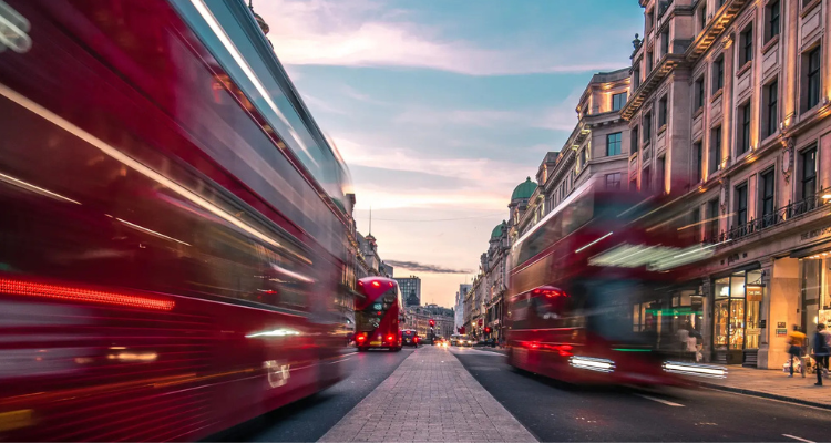 Blurred image of London's double decker busses passing one another in the street at dusk.
