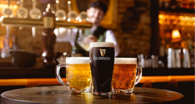 A pint of Guinness and two pints of beer on the table of a tavern.