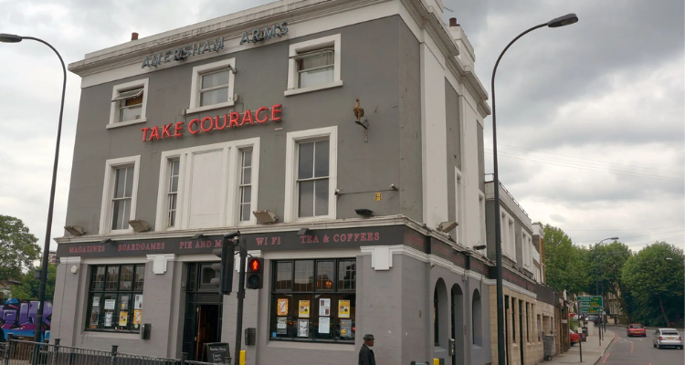 The exterior of The Amersham Arms with a neon sign reading 'Take Courage.'