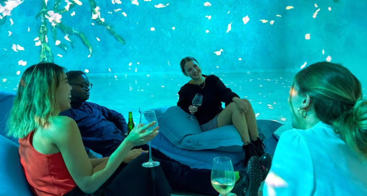 Four friends sitting on beanbags drinking wine and laughing at Frameless.