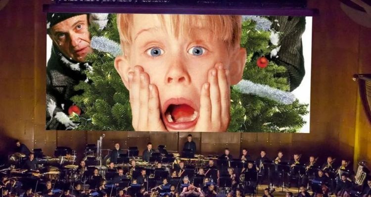 A still from Home Alone on a cinema screen with an orchestra in front.