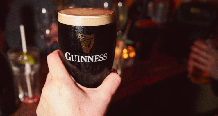 A pint of Guinness held in a dark pub. 