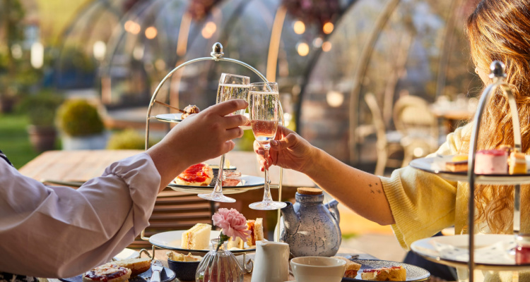 Glass clinking over afternoon tea with igloos in the background at Coppa Club London Bridge.