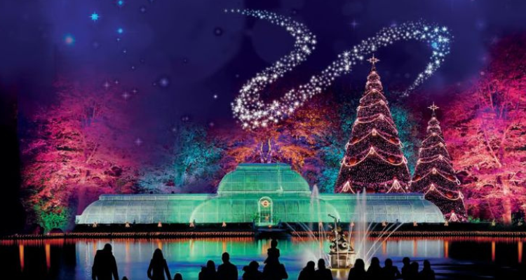 People looking at a beautiful Christmas display with a greenhouse and tree covered in lights at Kew Gardens.