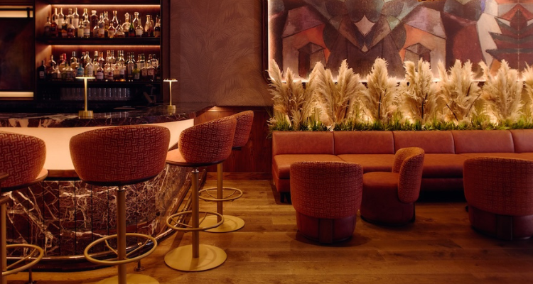 The interior of a fancy martini lounge with low lights, bar seating and a lounge area.