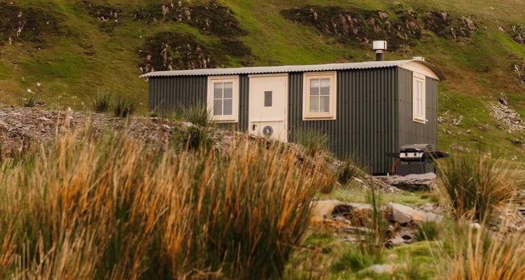 The exterior of our pretty shepherd's hut, surrounded by mountains..