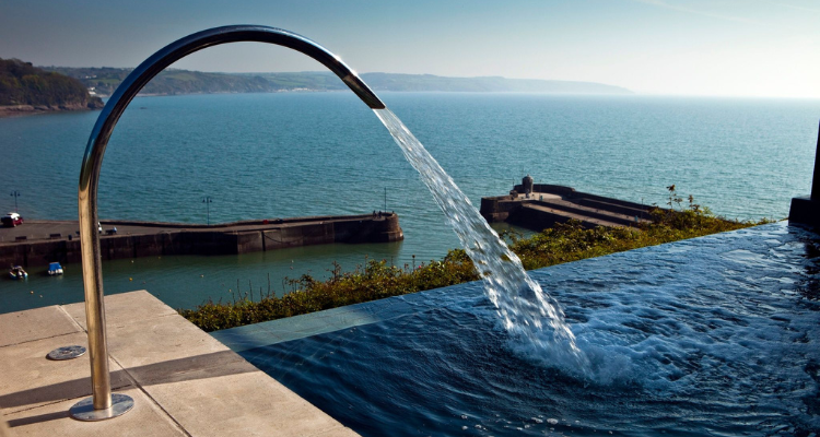 a faucet pouring water into an infinity pool that overlooks the bay.