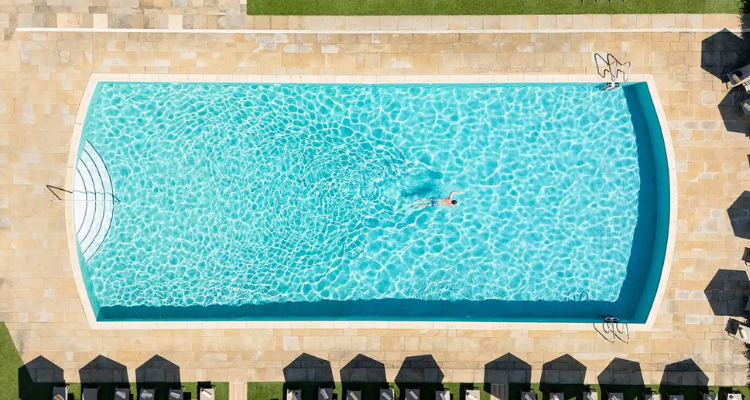 An aerial of someone swimming in a large hotel pool.