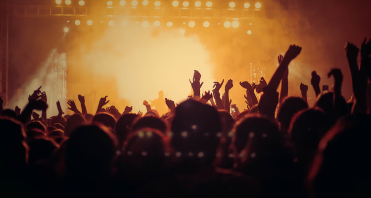 The shadows of a crowd dancing under yellow light at a club.