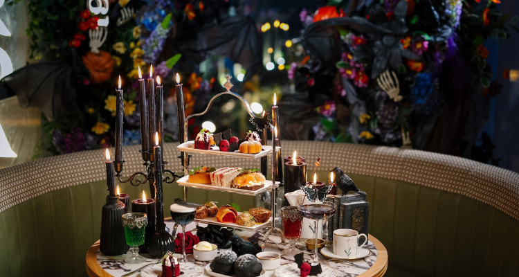 A Halloween-themed afternoon tea set up with themed snacks, desserts, and candles.