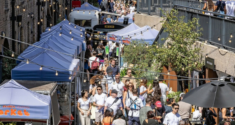 A crowd of people exploring market stalls in King's Cross.