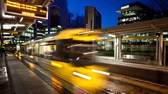Transport For Greater Manchester tram pulling in at MediaCityUK tram stop on New Year's Eve.