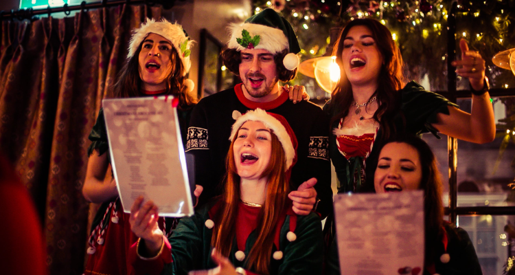 People dressed in festive clothes singing carols together.