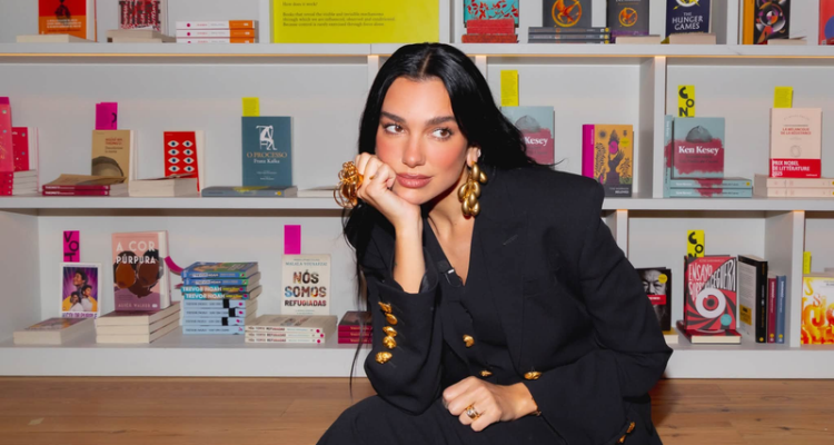 Dua Lipa in front of a bookcase.