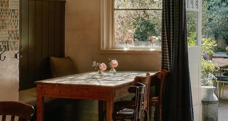 The inside of a pub featuring a wooden table and open window.