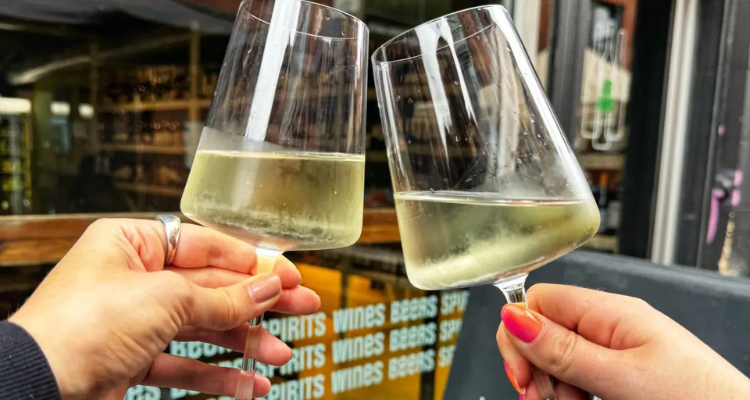 Two people clinking two glasses of white wine.